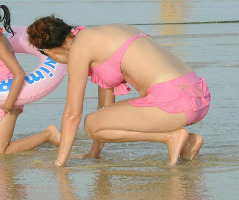 银沙海滩的泳装年轻妈妈