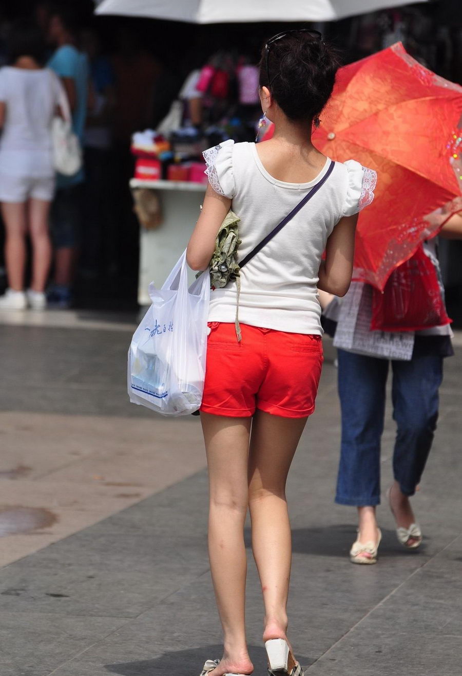 街拍一个打遮阳伞的红短裤女孩秀美腿