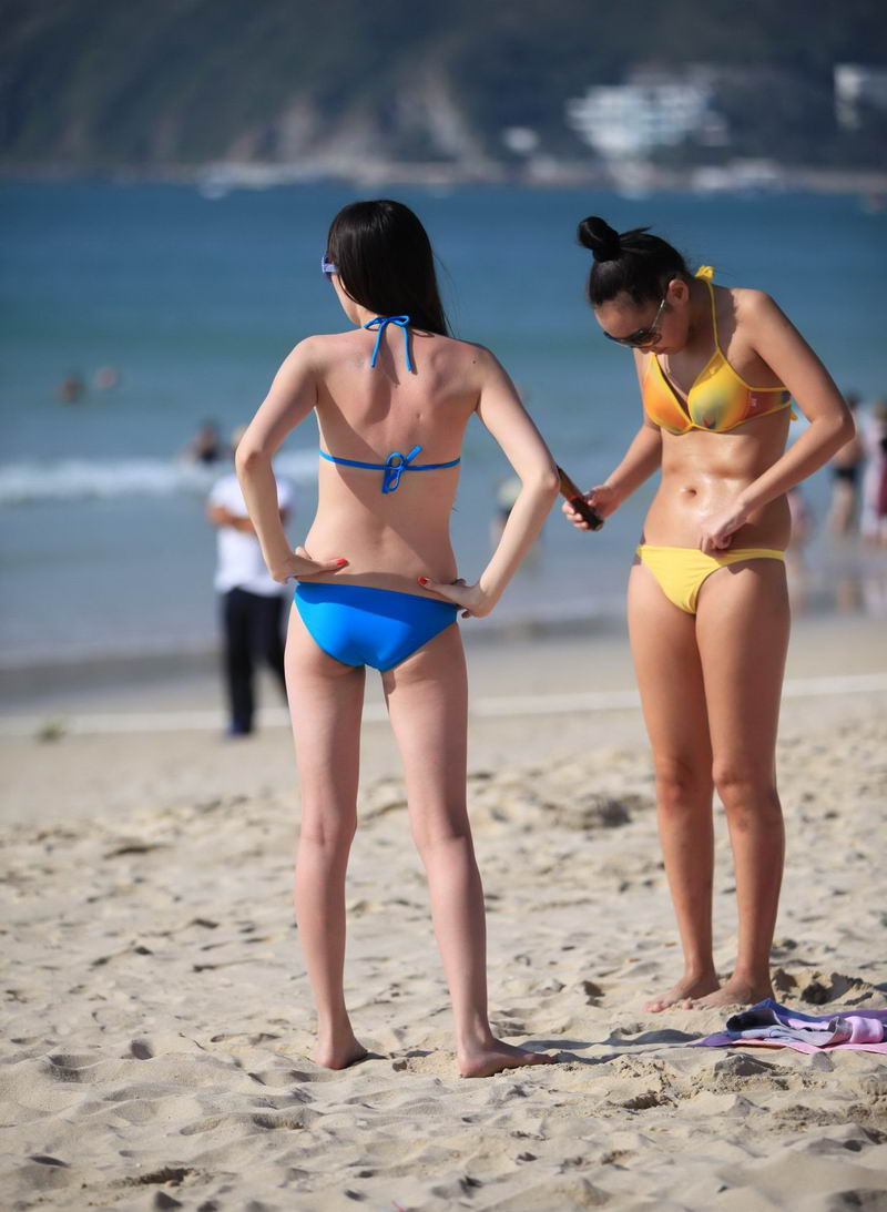 沙滩上抹防晒油的泳装女孩